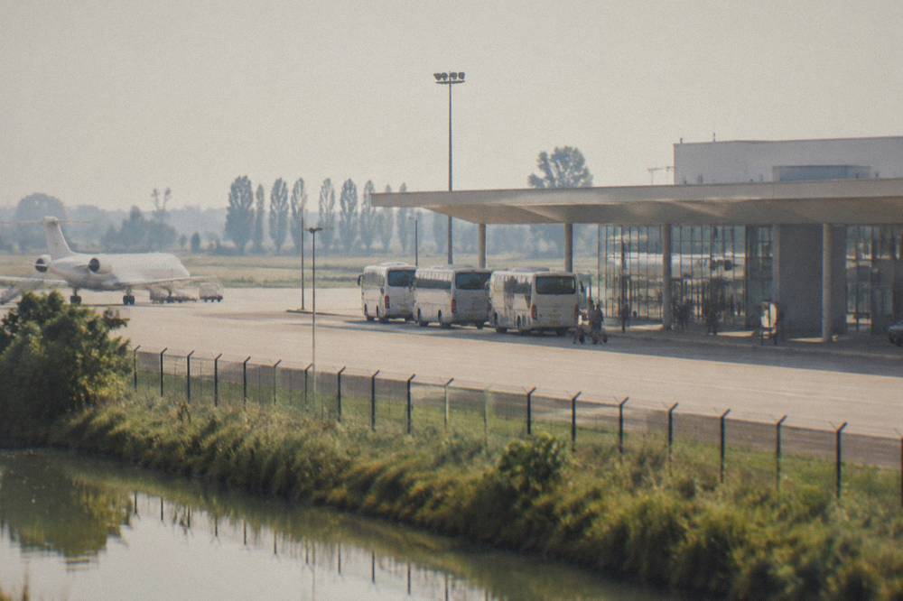 An airport departure board above a quiet terminal concourse