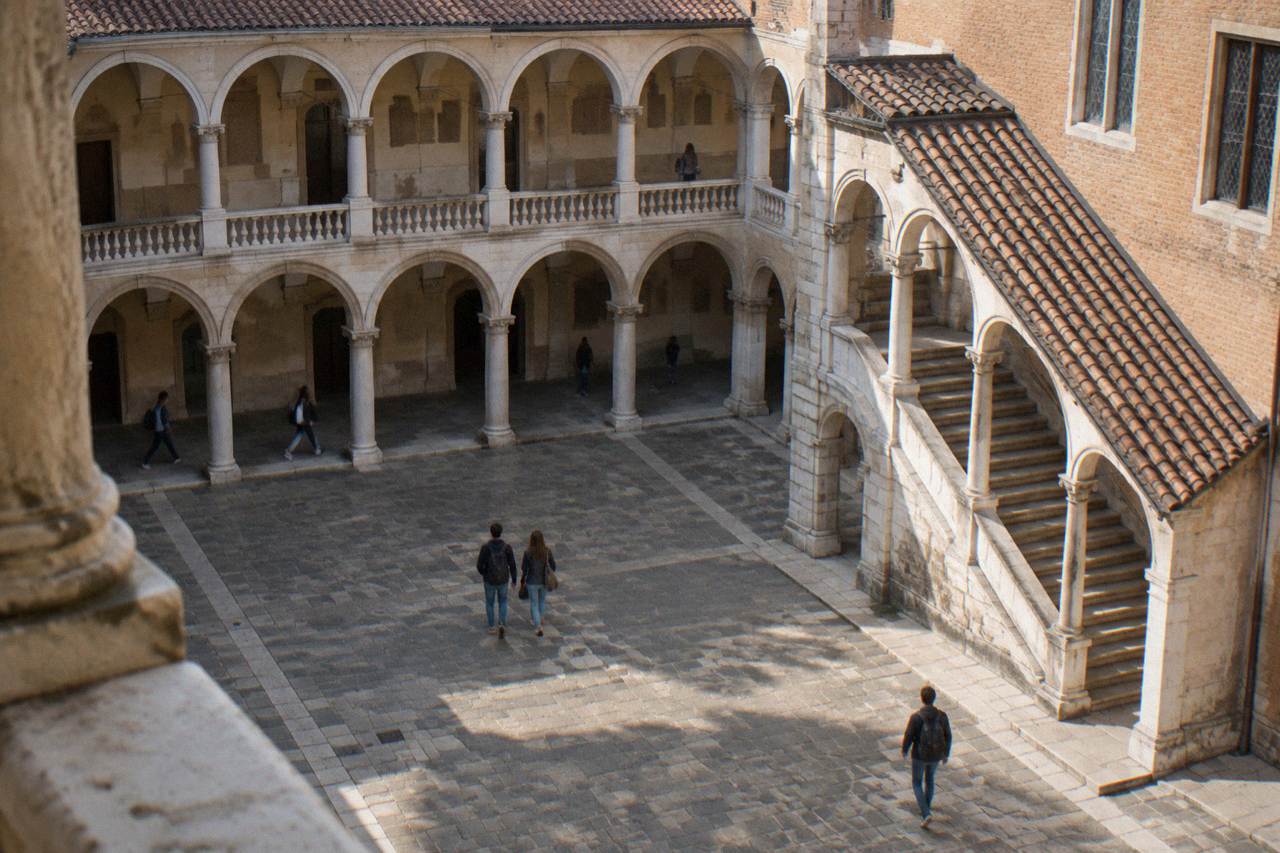 Historic university courtyard in Padua with arched loggias and worn stone steps