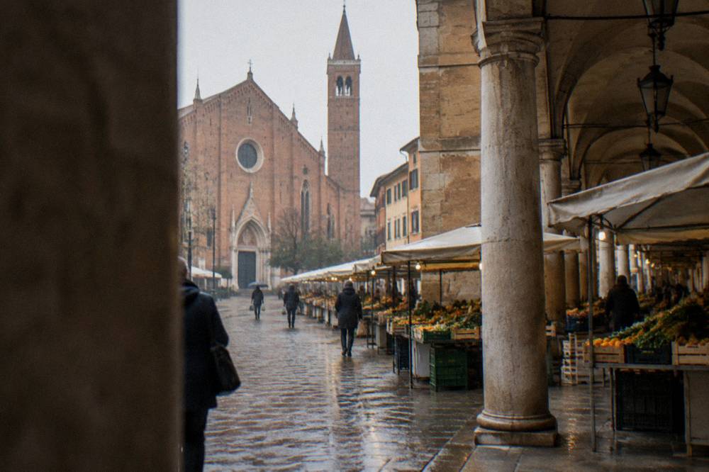 A covered market street with food stalls and old arcades in an Italian city centre
