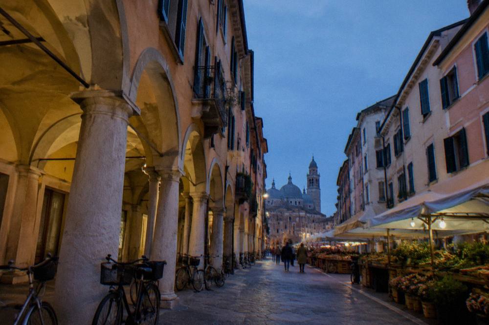 Arcaded street in central Padua with market awnings and bicycles