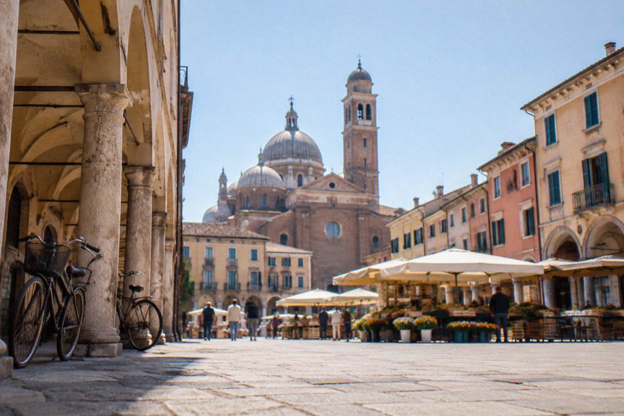Arcaded buildings and market awnings around a historic Paduan square in morning light