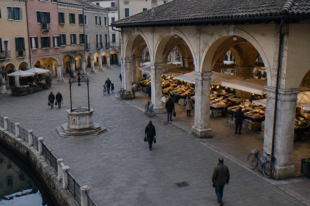 Market stalls under the covered hall of a Padua square on a grey day