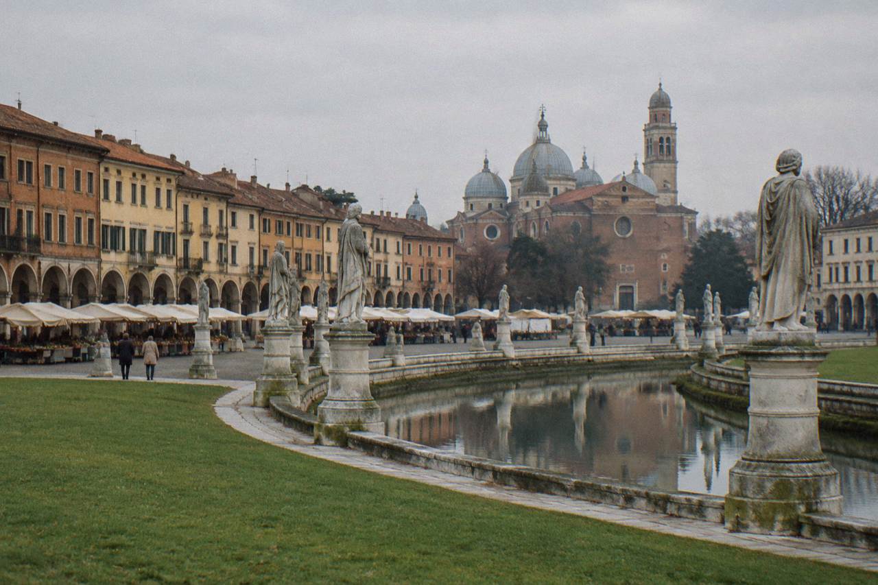 Arcaded square in Padua's old centre with market stalls and historic buildings
