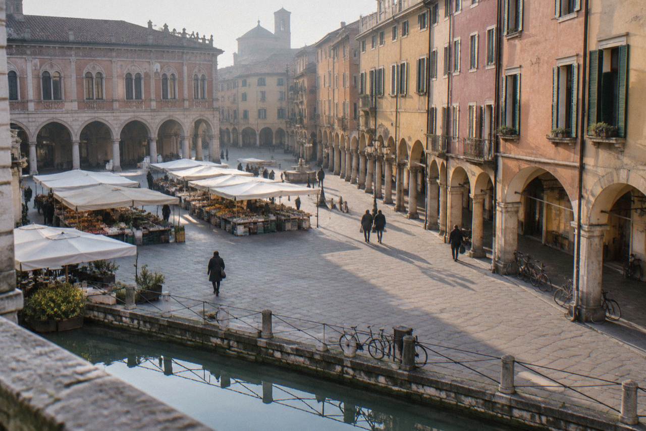 Arcaded square in Padua with market stalls and historic buildings under morning light