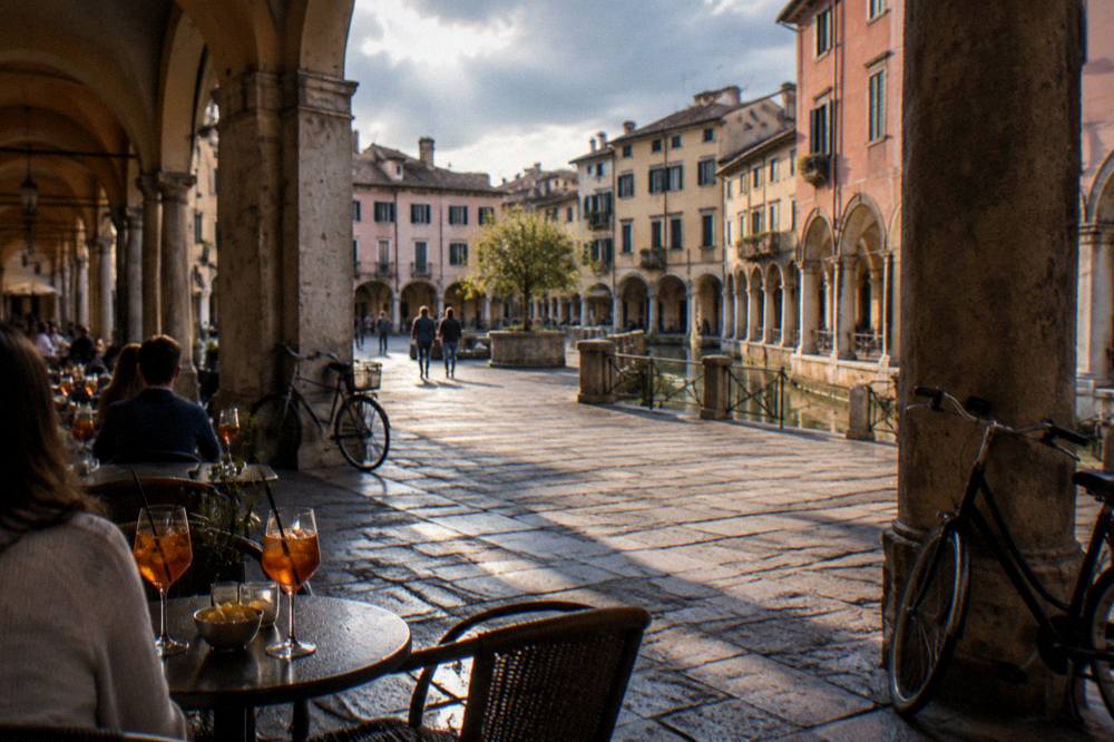 Evening tables and glasses of spritz under the arcades of a Padua square