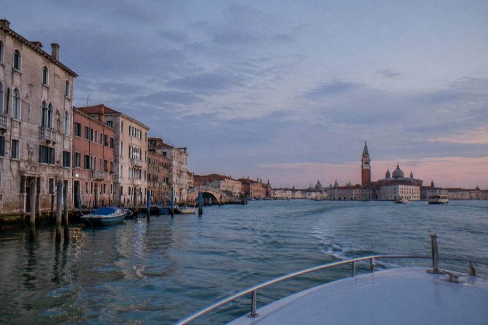 A boat approaching Venice across the lagoon with the city skyline ahead
