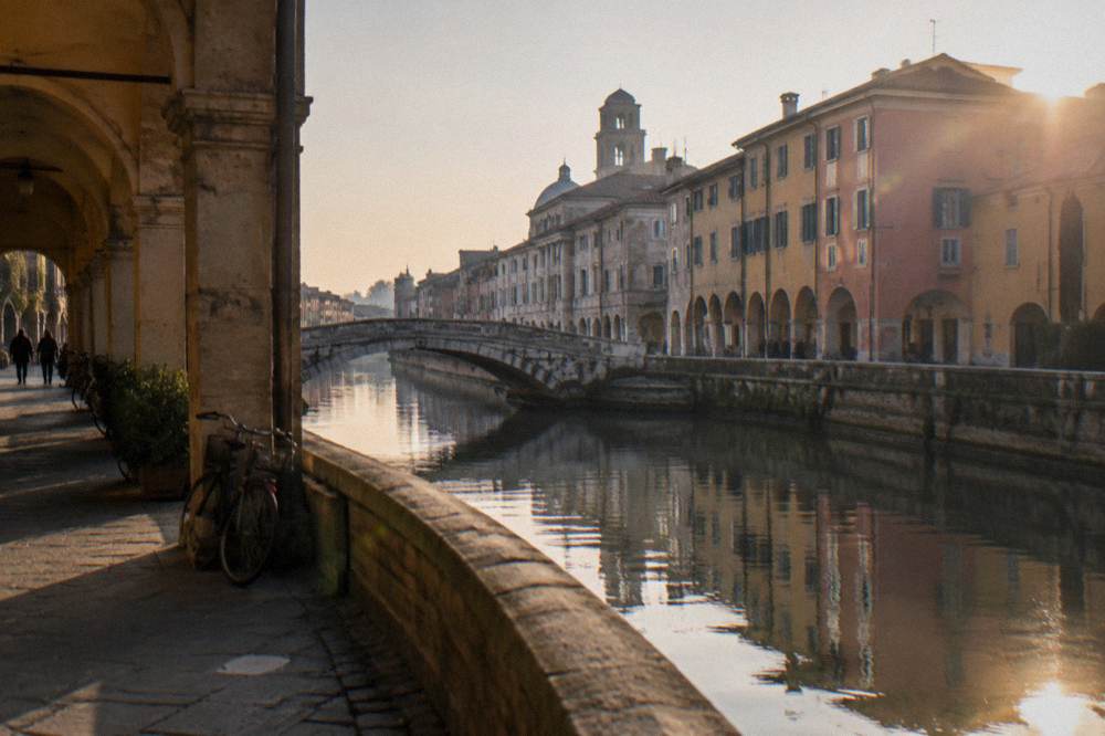 Canal with stone bridge and historic facades in Padua seen from the waterside path