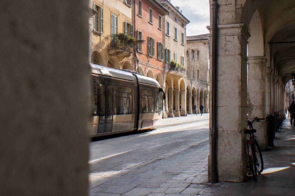 Modern tram travelling along a street in Padua past historic buildings