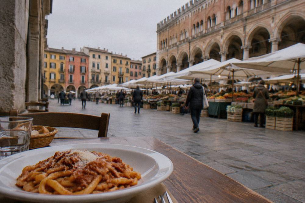 A plate of thick pasta with sauce on a wooden table in a small Italian eatery